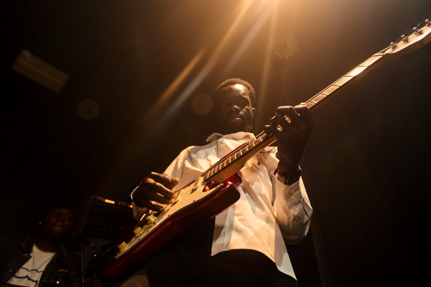 The bassist backlit in warm stage light.