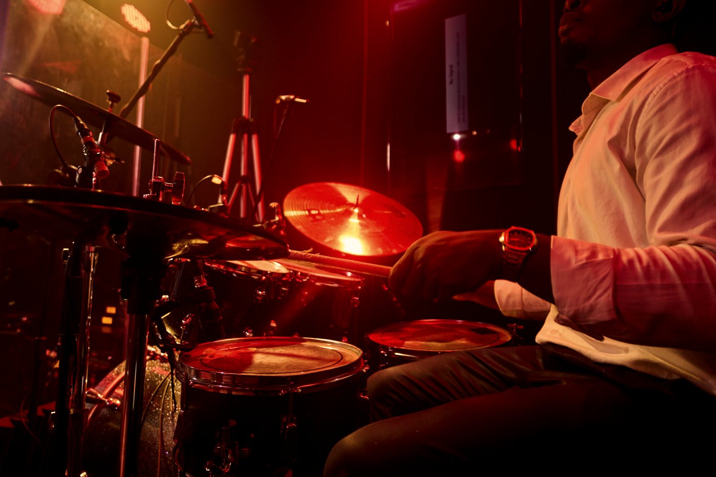 The drummer mid-take, lit red behind the cymbals.