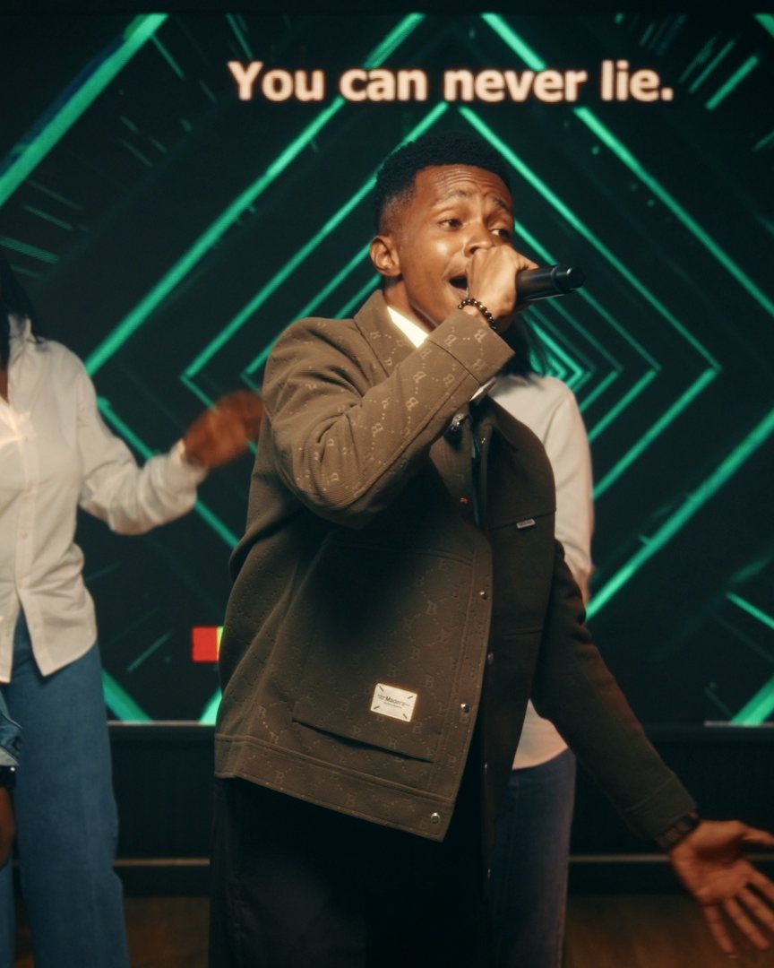 NWELL singing into the microphone as the lyric wall reads: You can never lie.