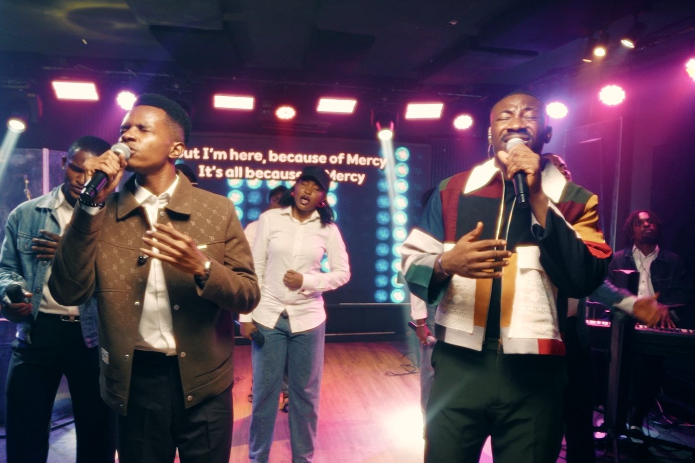 NWELL trading lines with a fellow vocalist as the lyric wall reads: It's all because of Mercy.